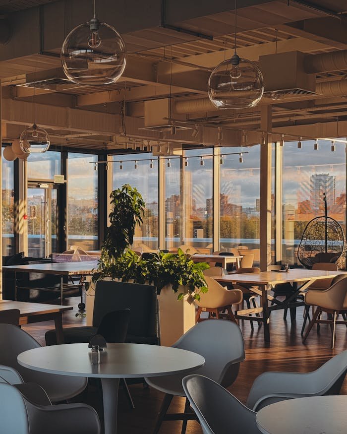 gallery-5 Warm modern cafe interior with urban view, stylish furniture, and cozy atmosphere captured during day.