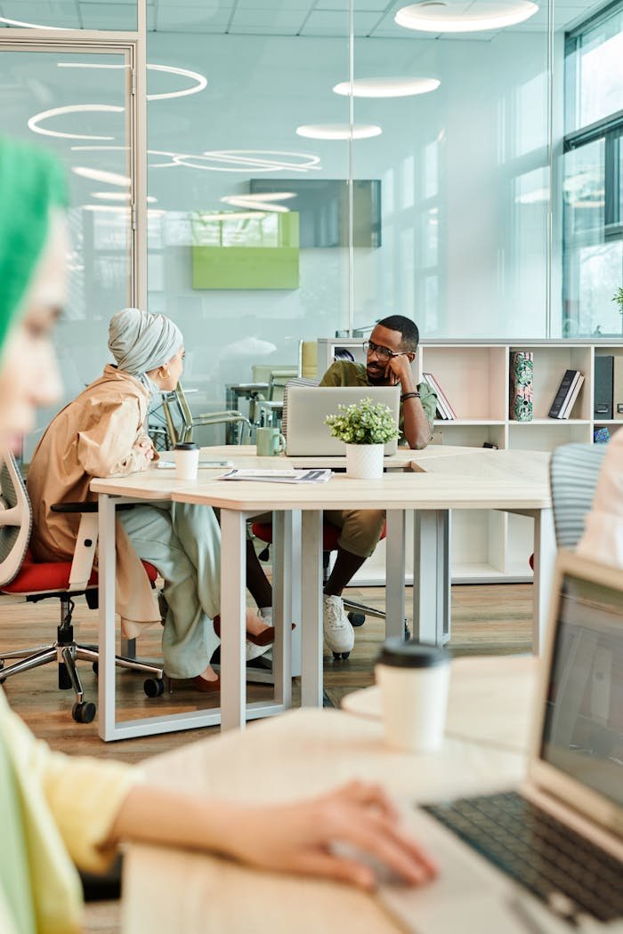 why-choose-us Diverse team collaborating in a modern office, engaging in conversation around desks.